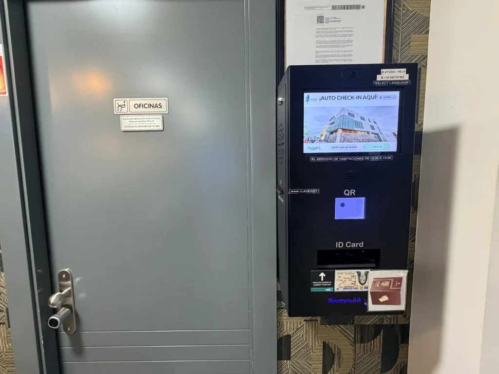Tótem de auto check-in junto a la puerta, con pantalla, lector de QR y lector de documento