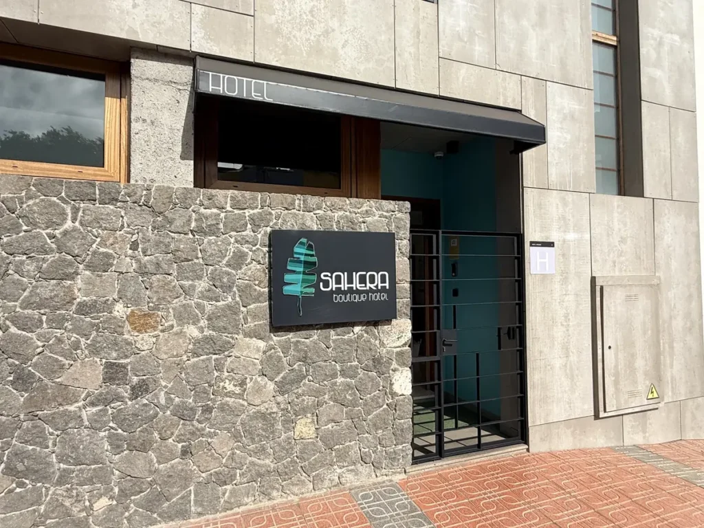 Acceso a SAHERA desde la calle: muro de piedra volcánica con el letrero del hotel y la cancela de entrada