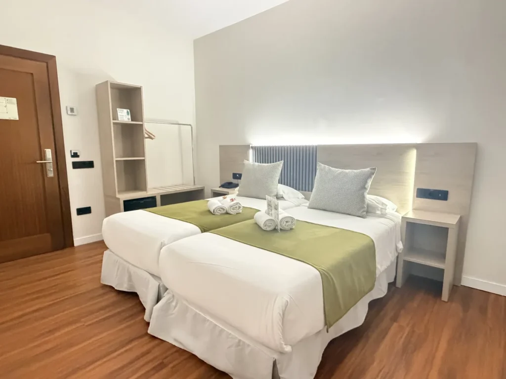 Habitación 101 adaptada vista desde la ventana: camas unidas, armario abierto y puerta de entrada