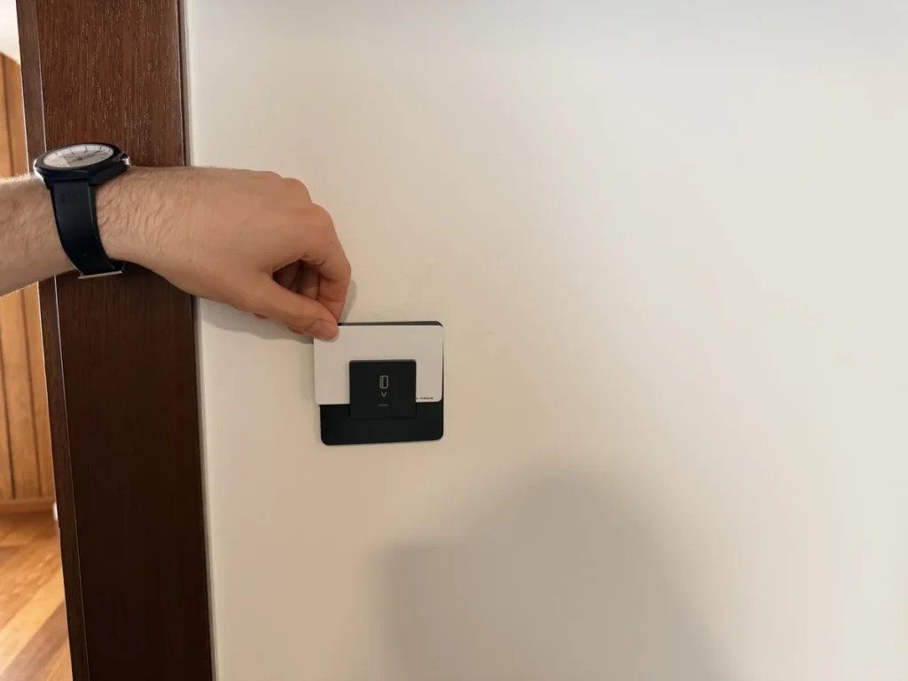 Mano metiendo la tarjeta de la habitación en el portatarjetas de la pared para encender la luz