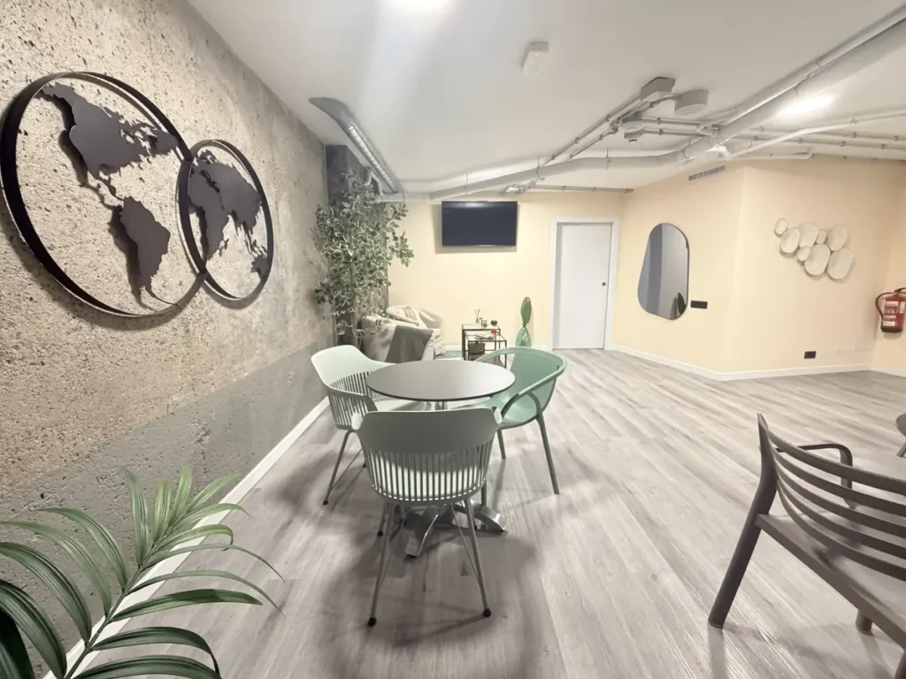 Mapamundi de metal en la pared del salón de usos múltiples, con mesas y plantas