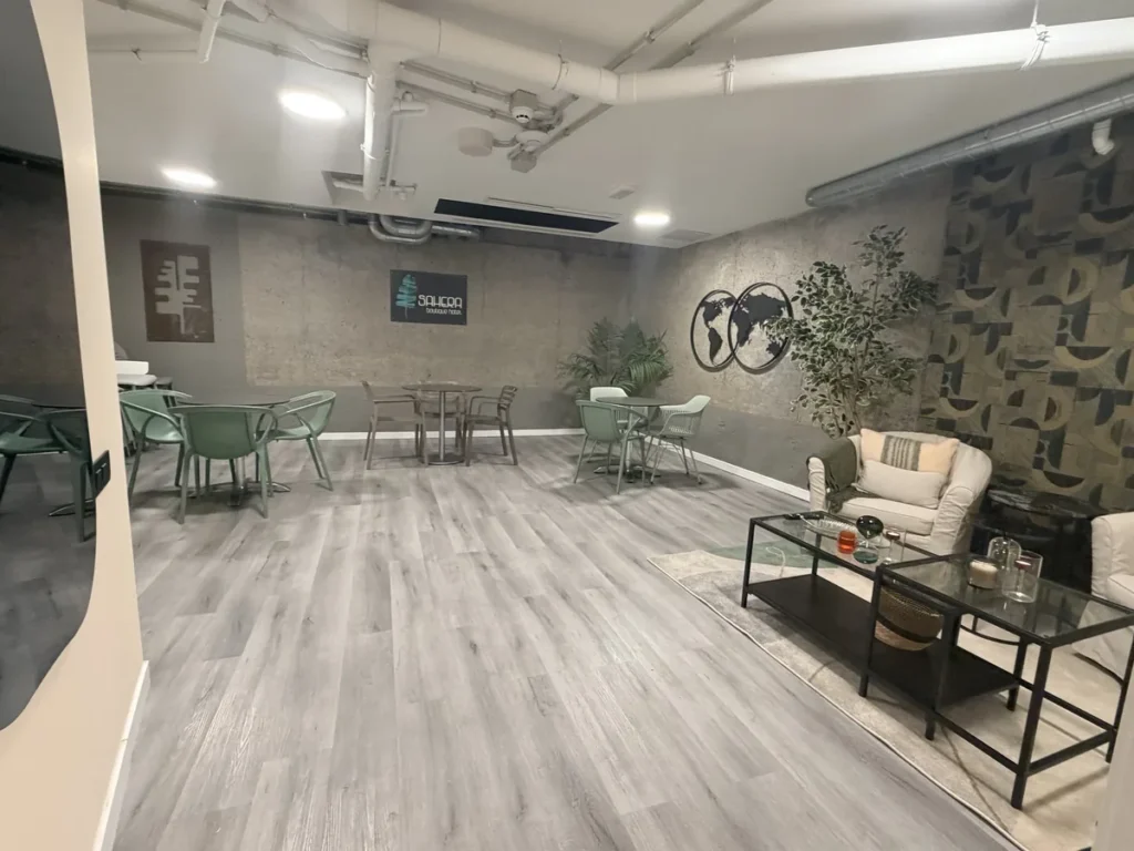 Vista general del salón de usos múltiples: zona de mesas al fondo y sillones en primer plano